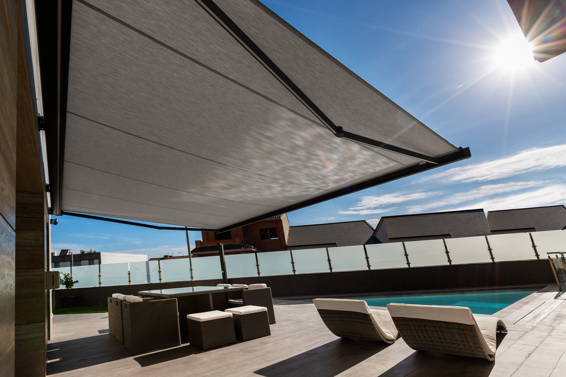 Pérgola con cubierta textil retráctil instalada en jardín residencial con mobiliario exterior