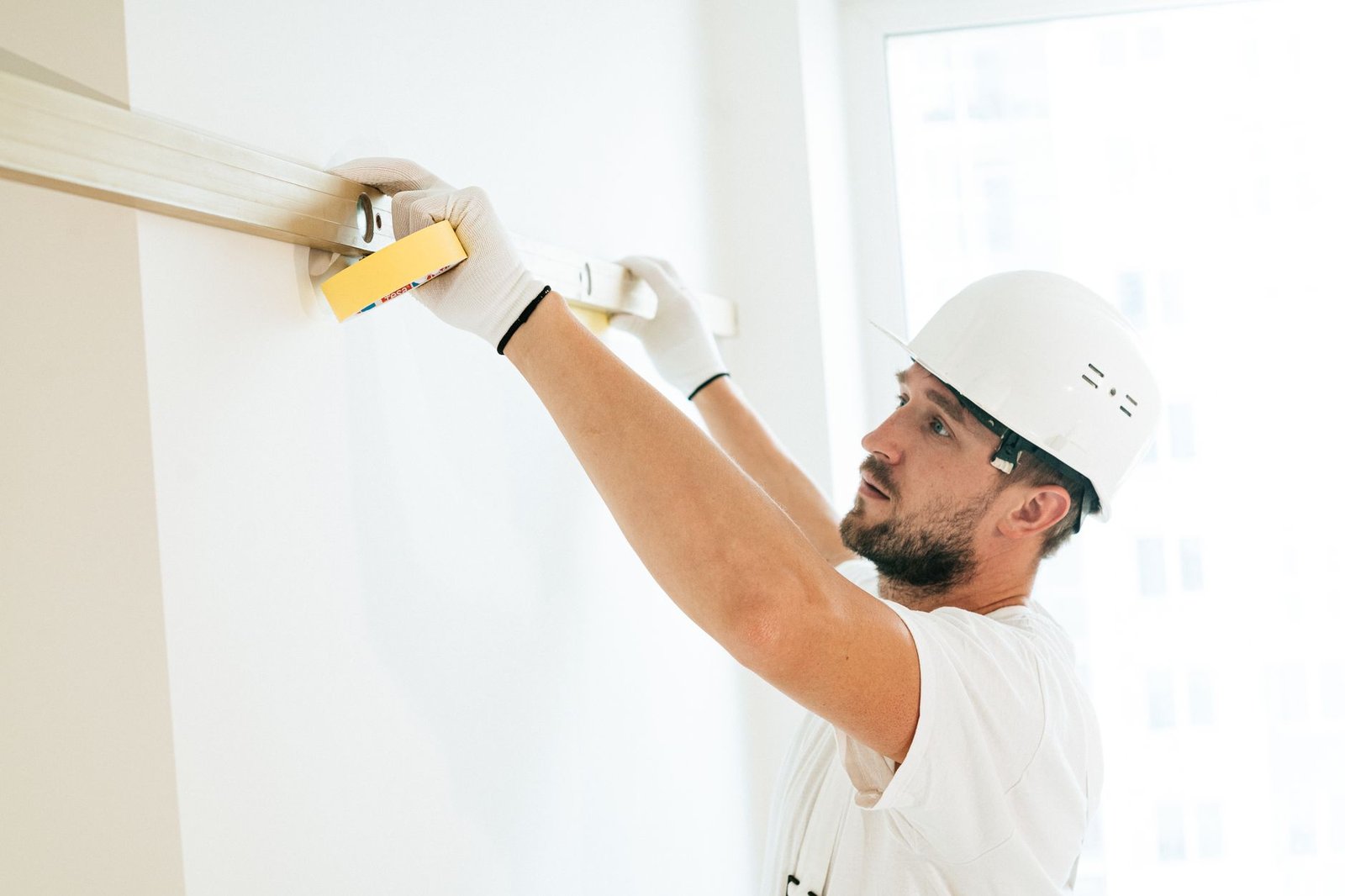 Instalador comprobando con nivel el aplomado de un marco en obra